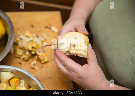 Quince Fruit mit Händen auf hellem Hintergrund mit Platz für eine Beschriftung geschält. Frau schält Quitte . Stockfoto