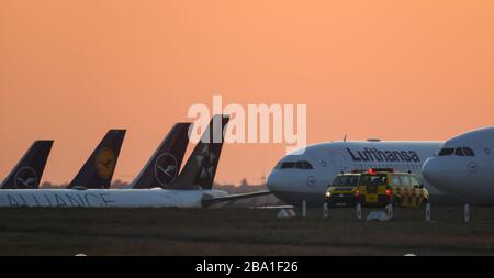 25. März 2020, Hessen, Frankfurt am Main: Lufthansa Passagierflugzeuge stehen auf der geschlossenen Landebahn nordwestlich des Frankfurter Flughafens vor dem orange-roten Abendhimmel. Die Lufthansa parkte während der dortigen Corona-Krise nicht benötigte Jets. Foto: Arne Dedert / dpa Stockfoto