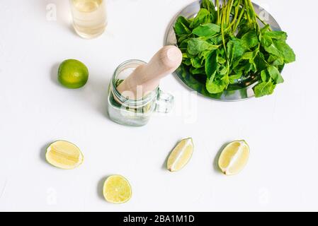 Geschnittene Kalkscheiben und Minzblätter auf einem weißen Tisch. Mojito Wird Gekocht. Flache Lage, Draufsicht Stockfoto