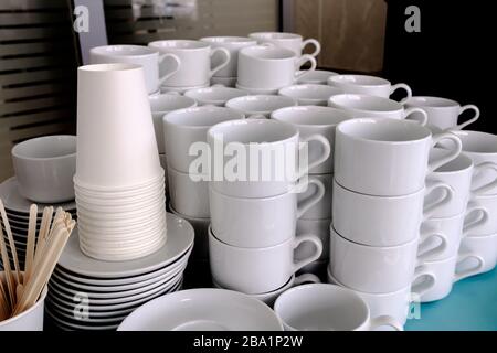 Belichtet auf Stapeln von weißen, sauberen Keramikbechern und Untertöpfen. Die Gerichte im Restaurant werden für Teetrinken und Kaffeetrinken zubereitet. Stockfoto