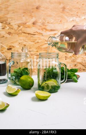 Mojito Wird Gekocht. Der Barmann gießt Sirup in einen Glascocktail mit gestampfter Minze und Kalk. Zutaten für die Herstellung von Mojito Stockfoto