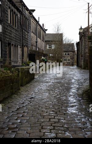 Typisches Bild der aus Stein erbauten Cottages aus Yorkshire Terraced und der gepflasterten Straße in Heptonstall, West Yorkshire im Calderdale Borough an einem nassen Tag Stockfoto