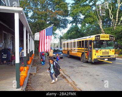 Schulkinder, die einen Schulbus außerhalb von Alley's General Store, West Tisbury, Martha's Vineyard, Massachusetts, USA, verlassen Stockfoto