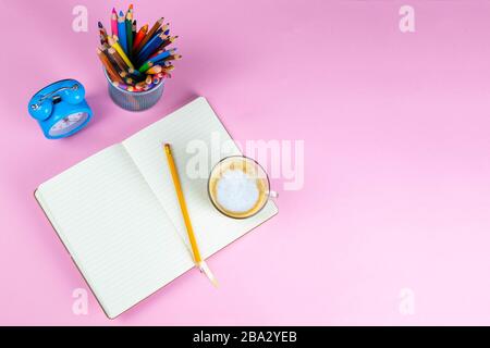 Bleistifte, Notizbuch und Uhr auf dem rosafarbenen Tisch. Geschäftskonzept. Stockfoto