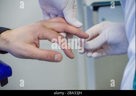 Der Mensch gibt Blut. Blut wird von einem Mann zur Analyse von einem Finger in einem spezialisierten medizinischen Labor entnommen. Behandlung Stockfoto