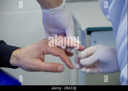 Der Mensch gibt Blut. Blut wird von einem Mann zur Analyse von einem Finger in einem spezialisierten medizinischen Labor entnommen. Behandlung Stockfoto