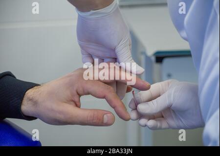 Der Mensch gibt Blut. Blut wird von einem Mann zur Analyse von einem Finger in einem spezialisierten medizinischen Labor entnommen. Behandlung Stockfoto