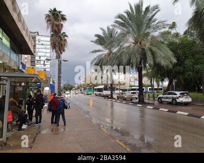 HOLON, ISRAEL. Januar 2020. Typische israelische Bushaltestelle auf der Eilat Straße in Holon, dem nächsten Vorort von Tel Aviv. Leute, die an einem regnerischen Tag auf den Bus warten Stockfoto