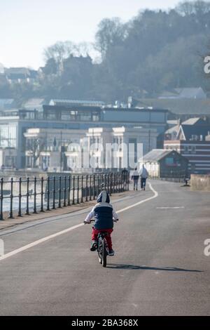 Der kleine Junge auf seinem Fahrrad wird täglich auf der meist belebten Strandpromenade von Mumbles trainieren. Ein Regierungsabsturz ist wegen einer Covid-19-Pandemie und p Stockfoto