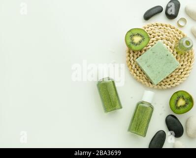 Shampoo, flüssige Seife, Kiwi-Früchte und Spa-Steine, männlicher Ring, Seifenleiste auf Hassockmatte isoliert auf weißem Hintergrund mit Kopierraum. Spa aromatische Toile Stockfoto