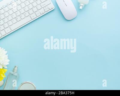 Freiberufliche Frau Blogger Arbeitsplatz, Arbeitsplatz, Tastatur, Maus-Laptop, Parfüm-Kosmetik-Flaschen isoliert auf hellblauem Tischhintergrund mit Kopie Stockfoto