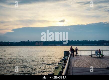 New York, NY/USA - 13. Juli 2014: Die Menschen genießen den Sonnenuntergang am Pier 84 Dock in Manhattan. New Jersey steht im Hintergrund. Stockfoto