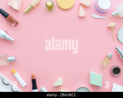 Kurative und dekorative Produkte isoliert auf pinkfarbenem Hintergrund. Lippenstifte, Lippenbalsam, nagelpoliermittel, falsche Wimpern, Parfüm, Augenschatten, Puffpulver, FAC Stockfoto
