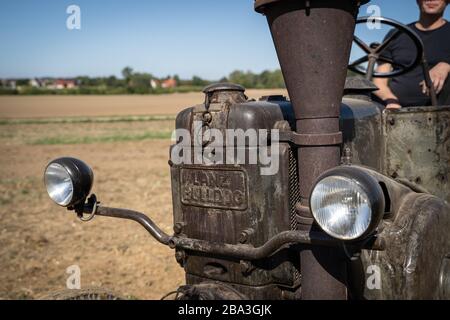 Der alte und alte Lanz Bulldog Tractorr, der mit einem Pflug auf den Feldern arbeitet und zeigt, wie die Landwirtschaft vor vielen Jahren erfolgte. Stockfoto