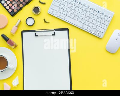 Tastaturmaus, Tasse Tee- und Schminkwerkzeuge und Kosmetikprodukte rund um sie isoliert auf einem gelben Hintergrund. Flaches Layout, Kopierbereich in der Draufsicht. Feminin Stockfoto