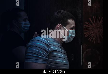 Mann und Frau in medizinischen Masken stehen in der Nähe der Tür gegen COVID-19 Stockfoto