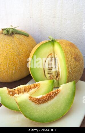 Zwei Scheiben Cantaloupe Melon (Cucumis melo cantalupensis) zusammen mit zwei Teilen dieser Melonenart Stockfoto