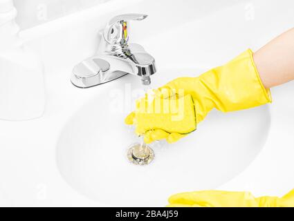 Frau in gelben Gummihandschuhen ist die Reinigung des Badezimmerwaschkörpers mit Waschmittel und Schwamm Stockfoto