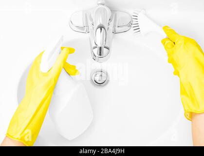 Frau in gelben Gummihandschuhen ist die Reinigung des Badezimmerwaschkörpers mit Waschmittel und Schwamm Stockfoto
