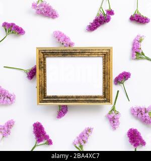 Antiker Bilderrahmen mit pinkvioletten Statikblüten auf weißem Hintergrund. Blumendesign, flacher Lay, Draufsicht, Kopierbereich Stockfoto