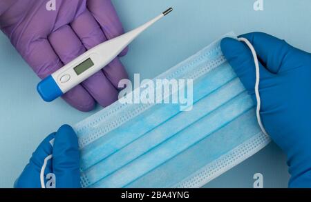 Coronavirus Prävention chirurgische Masken und handelektronisches Thermometer zur Messung der Körpertemperatur. Draufsicht. Stockfoto