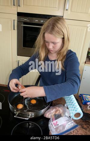 Mädchen in der Vorzeit knackt Eier in der Pfanne, um das Frühstück in der Küche zu kochen. Zawady Gmina Rzeczyca Polen Stockfoto