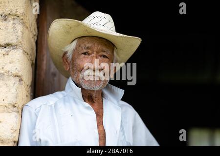 El Chorrito, Tamaulipas, Mexiko, 2. Juli 2019: Mexican Senior, in seinem adobe-haus, wartet vor seiner Tür Stockfoto