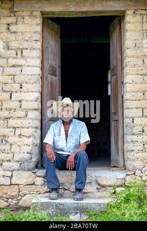 El Chorrito, Tamaulipas, Mexiko, 2. Juli 2019: Mexican Senior, in seinem adobe-haus, wartet vor seiner Tür Stockfoto