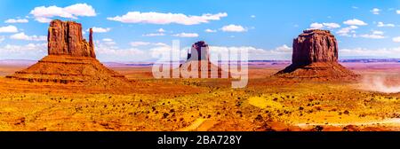 Panoramablick auf die Sandsteinformationen East und West mitten Buttes und Merrick Butte im Monument Valley Navajo Tribal Park im Süden Utahs, Uni Stockfoto