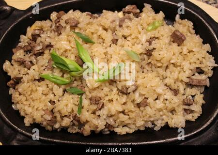 Gericht aus Reis mit Scheiben Roastbeef und grünen Zwiebeln Stockfoto