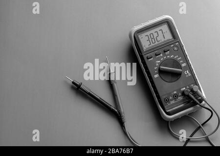 Ein Multimeter mit Daten auf dem Display. Digitalmultimeter mit Messspitzen auf grauem Hintergrund, ein Multimeter ist ein elektronisches Messgerät. Ansicht von fro Stockfoto