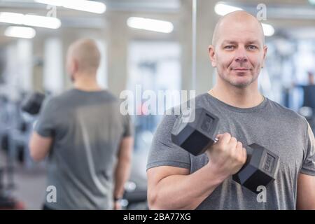 Junger Muskelmann oder Trainer, der im Fitnessstudio trainiert. Stockfoto