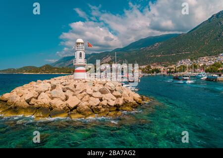 Leuchtturm an einem sonnigen Morgen mit Fischerbooten am Hafen von Kas Türkei Stockfoto