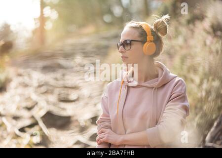 Porträt einer schönen Sportfrau, die während des Trainings im Freien Sonnenbrille, Hoodie und Kopfhörer trägt Stockfoto