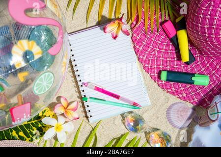 Leere Schreiben von Notizen mit rosa und grünen Stift auf Sand, umgeben von grünen Palmen treibt, Meer shelles, rosa Hut, aufblasbare Spielzeuge. Sommer Strand backgroun Stockfoto
