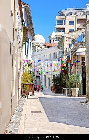 LIMASSOL, ZYPERN - 05. MÄRZ 2019: Fußgängerzone mit buntem Fähnrich, Café-Tischen und Stühlen in der Altstadt an einem sonnigen Tag Stockfoto