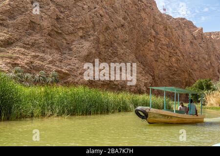 Ein kleines Boot, das Touristen zu Beginn der Wanderung nach Wadi Shab im Oman über den Fluss führt. Stockfoto