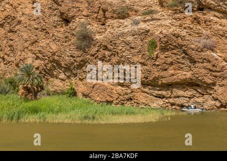 Ein kleines Boot, das Touristen zu Beginn der Wanderung nach Wadi Shab im Oman über den Fluss führt. Stockfoto