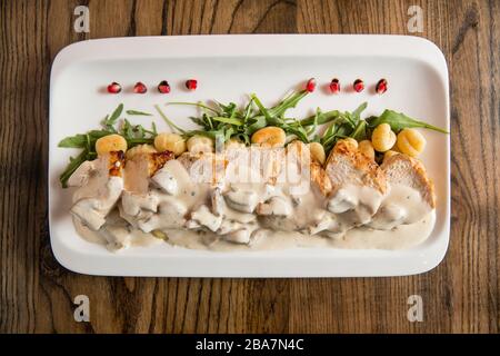 Huhn auf geriebenem Gnocchi in Sahnesauce aus Pilzen und Räucherkäse auf dem Tisch Stockfoto