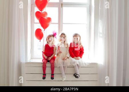 Drei Mädchen Freundinnen sitzen am Fenster mit Luftballons Stockfoto