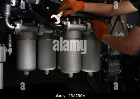 Low Key Foto von Hydraulikleitungen Wartungsarbeiten an schweren Branche Maschinen in der Garage. Stockfoto