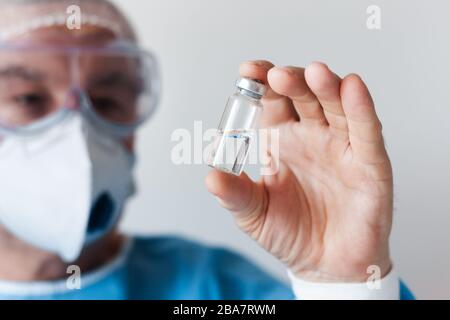 Coronavirus Covid-19-Konzept. Ein Arzt in einer Brille und eine Atemschutzmaske zum Schutz halten eine Impfstoffflasche. Wuhan, China Epidemie Virus COV-19 sympto Stockfoto