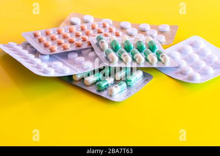 Sechs Blasen generischer Tabletten gelber Hintergrund.Pillen in Packungen.verschiedene Medikamente.Pharmazeutische Industrie.Gesundheitswesen und Lagermedizin. Stockfoto