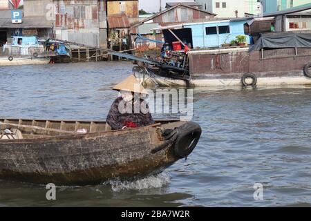 VIETNAMESISCHE LEUTE, DIE WAREN AUF DEM MEKONG FLUSS IM DELTA, VIETNAM TRANSPORTIEREN UND HANDELN. Stockfoto