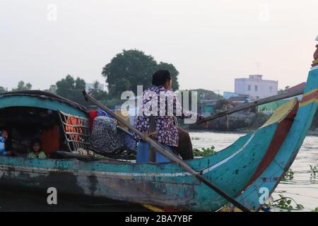 VIETNAMESISCHE LEUTE, DIE WAREN AUF DEM MEKONG FLUSS IM DELTA, VIETNAM TRANSPORTIEREN UND HANDELN. Stockfoto