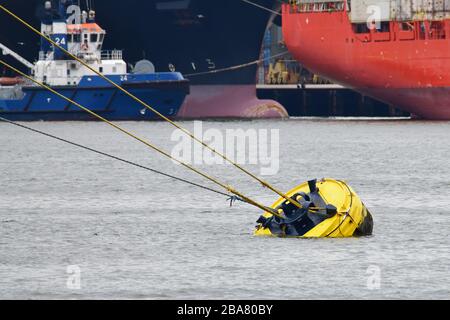 Nahaufnahme der leuchtend gelben Anlegeboje mit Seilen zum Schiff im Hafen im Containerterminal Stockfoto