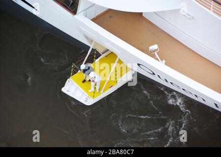 high above view of section of bow of cruise ship Queen Elisabeth arriving in Rotterdam. Staff member standing on small bridge on bow to monitor dockin Stockfoto