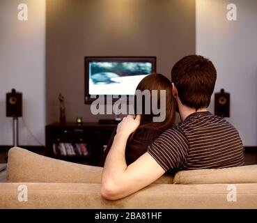 Selbstisolation in einem Quarantänehaus eines jungen Paares während einer Coronavirus-Pandemie. Ein Mann und ein Mädchen sehen gerade Fernsehen. Stockfoto