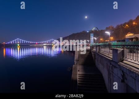 Blick über die Fußgängerbrücke über den Fluss Dnipro in Kiew bei Nacht Stockfoto