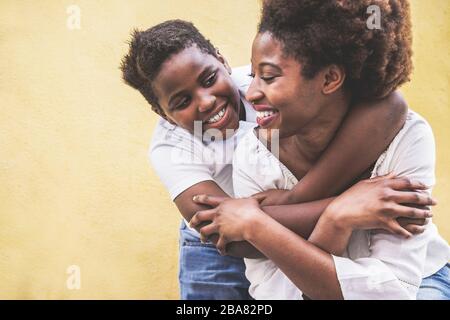 Fröhliche junge Mutter hat Spaß mit ihrem Kind - Son umarmt seine Mutter im Freien - Familienleben, Mutterschaft, Liebe und zärtliche Momente Konzept Stockfoto